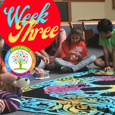 Children seated on the floor around a large colourful fabric