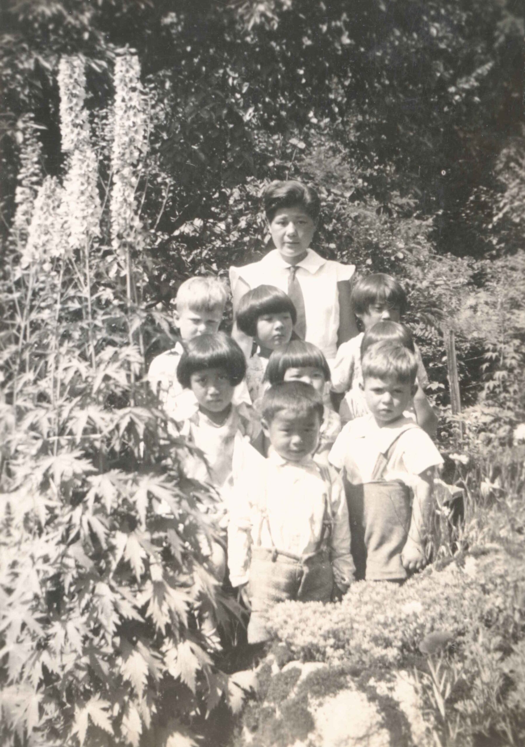 Japanese Canadian kindergarten teacher Miss Teruko Hidaka with her students in the Fraser Valley, likely Whonnock.<br><br><i>PMRC Archives Reference collection, item BCCA 2-246</i>